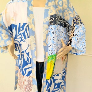 Puede incluir: Un kimono de estampado floral azul y blanco con un diseño de patchwork. El kimono tiene manga larga y un cinturón de atar.