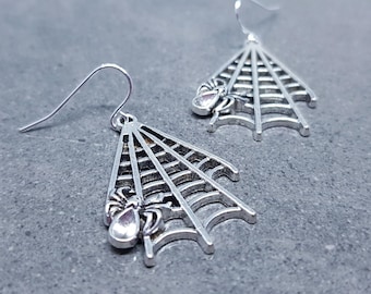 May include: A pair of silver spider web earrings with a small spider detail. The earrings are dangle style and have a hook closure.