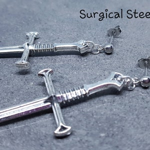 Peut inclure: Une paire de boucles d'oreilles en forme d'&eacute;p&eacute;e argent&eacute;es avec des tiges en acier chirurgical. Les &eacute;p&eacute;es ont un design d&eacute;taill&eacute; et sont un accessoire unique et &eacute;l&eacute;gant.