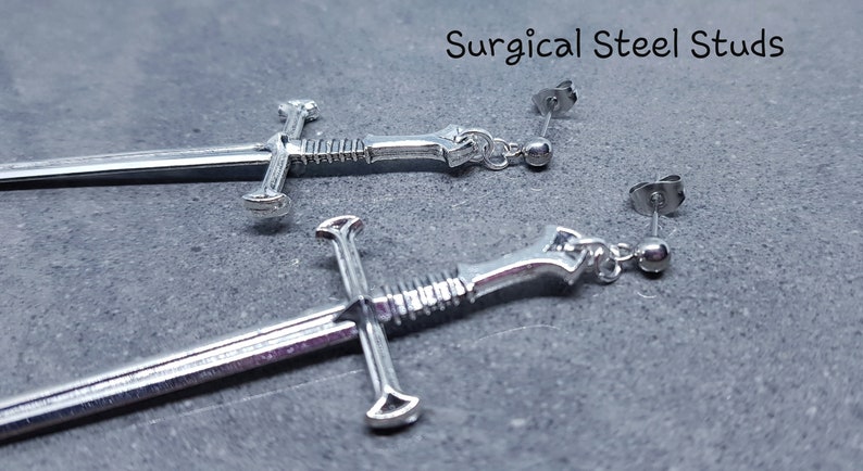 Peut inclure: Une paire de boucles d'oreilles en forme d'&eacute;p&eacute;e argent&eacute;es avec des tiges en acier chirurgical. Les &eacute;p&eacute;es ont un design d&eacute;taill&eacute; et sont un accessoire unique et &eacute;l&eacute;gant.