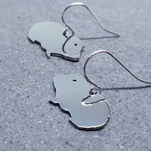 May include: A pair of silver dangle earrings featuring a guinea pig silhouette. The earrings have a simple, minimalist design.