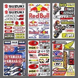 May include: A sheet of colourful motorcycle racing decals featuring logos for brands such as Red Bull, Suzuki, Yamaha, Honda, and NGK. The decals are printed on white paper and are ready to be applied to a motorcycle.