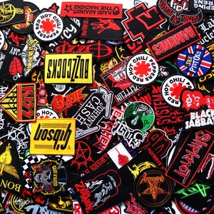 May include: A collection of embroidered patches featuring band logos and designs. Notable patches include "Red Hot Chili Peppers," "Ramones," "Black Sabbath," and "Johnny Cash." The patches are in various colors, including red, black, and white.