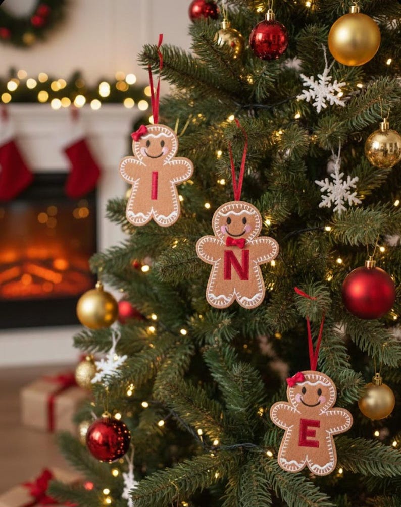 May include: Three felt gingerbread person ornaments hanging on a Christmas tree. Each ornament features white stitched icing details, a red ribbon loop, and a single red letter on the chest spelling out the word INE in a vertical arrangement.