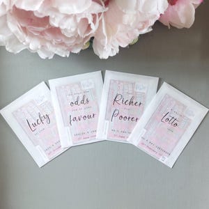 May include: Four rectangular white envelopes containing lottery tickets, each with black printed text. The envelopes feature phrases like Lucky in love, We hope the odds are in your favour, For Richer For Poorer, and a whole lotto love with names and dates.