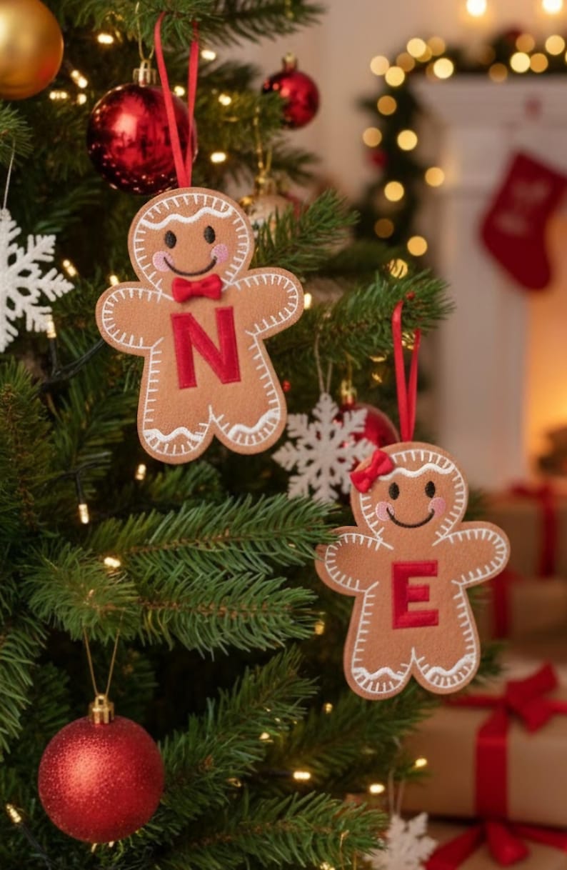May include: Two tan felt gingerbread person ornaments hanging from a Christmas tree. One ornament features a red letter N and a red bow tie, while the other features a red letter E and a red hair bow. Both have white stitched icing details.