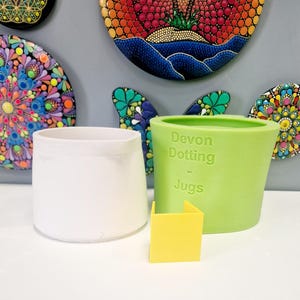 Puede incluir: Dos moldes de silicona para hacer jarras. El molde verde tiene el texto "Devon Dotting - Jugs" en el lateral. Un cuadrado amarillo está en primer plano.