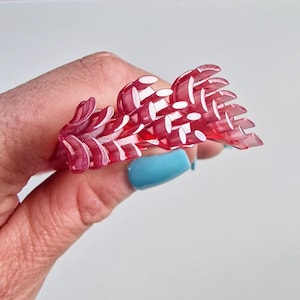 Może przedstawiać: Zbliżenie na obiekt 3D wydrukowany z czerwonego i białego plastiku. Obiekt ma kształt gałęzi z wieloma liśćmi.