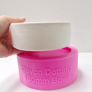 Op de afbeelding: Een roze siliconen mal voor een 130 mm kom. De mal heeft de woorden "Devon Dotting 130mm Bowl" in reliëf aan de zijkant.