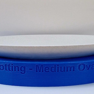 May include: A white oval platter sits on top of a blue oval base. The base is labeled "Devon Dotting - Medium Oval Platter".