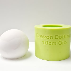Peut inclure: Un moule en silicone vert pour faire un orbe de 10 cm. Le moule est étiqueté "Devon Dotting 10cm Orb".