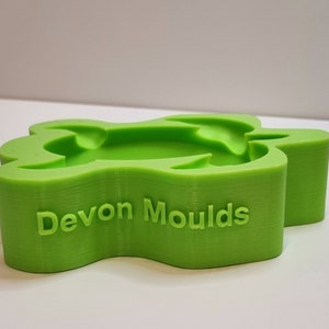 Könnte beinhalten: Eine grüne, schildkrötenförmige Form aus Kunststoff mit dem Text "Devon Moulds" auf der Unterseite.