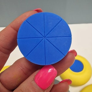 May include: A blue circular object with six evenly spaced lines radiating from the center. The object is made of a textured material and has a slightly raised edge.