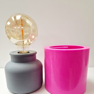 May include: A white ceramic mug with a black handle and the text "But First, Coffee" in a bold, black font. The mug is set against a blurred background, suggesting a cozy setting.