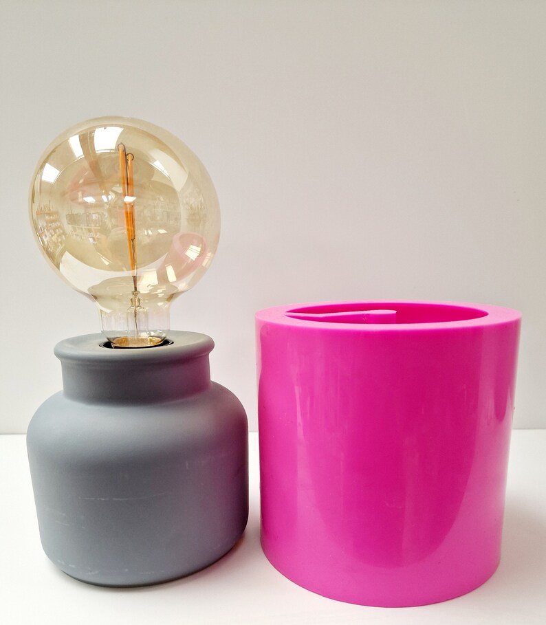 May include: A white ceramic mug with a black handle and the text "But First, Coffee" in a bold, black font. The mug is set against a blurred background, suggesting a cozy setting.