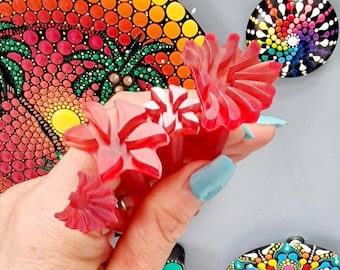 May include: A set of three red plastic dotting tools for creating mandala art. The tools are shaped like flowers and have different sized dots. The tools are being held in a hand with a light blue nail polish.