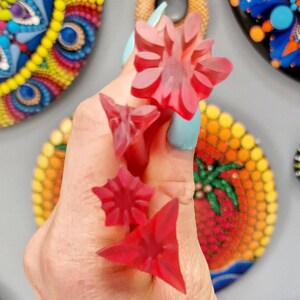 May include: Four red plastic dotting tools for creating dot art. The tools are shaped like a star, a flower, a triangle, and a smaller triangle.