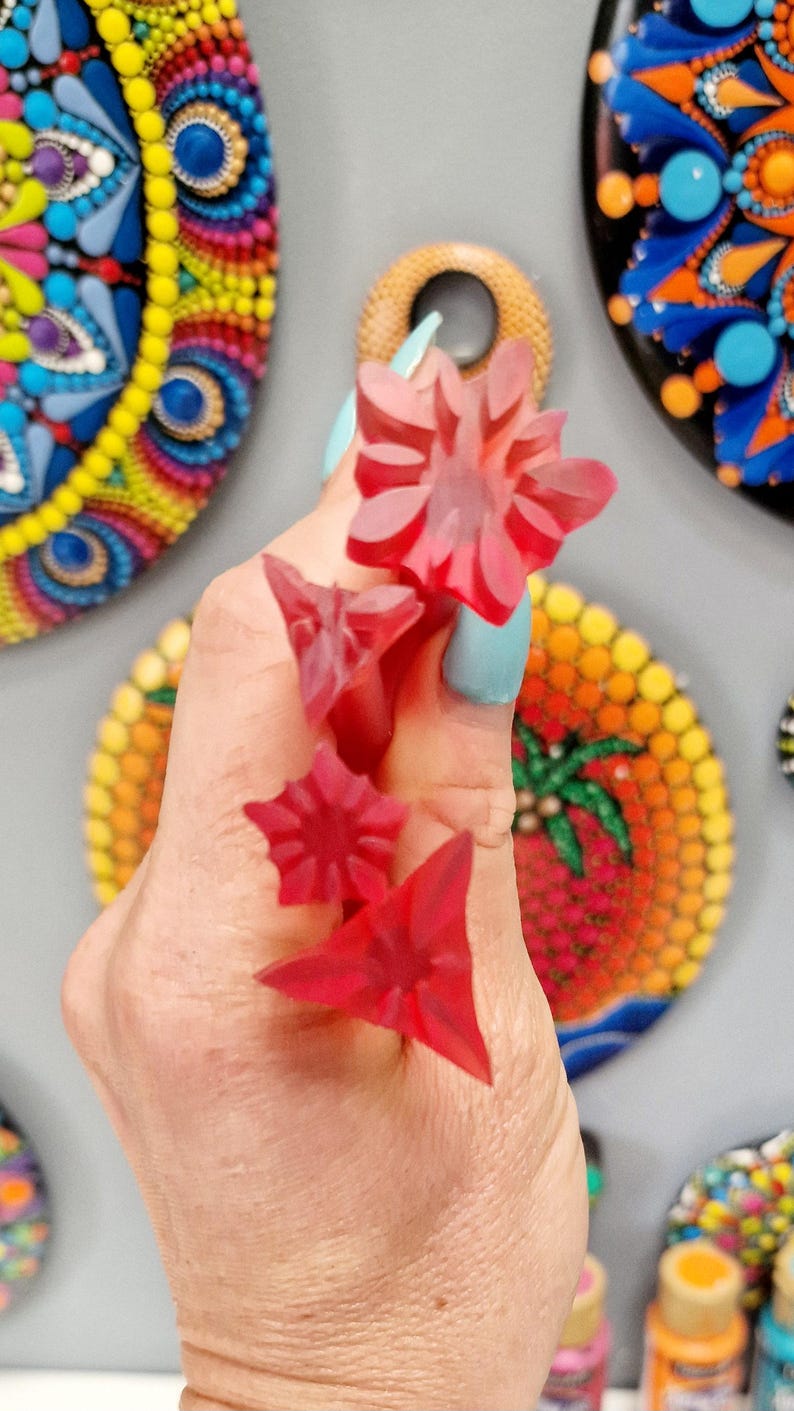 May include: Four red plastic dotting tools for creating dot art. The tools are shaped like a star, a flower, a triangle, and a smaller triangle.