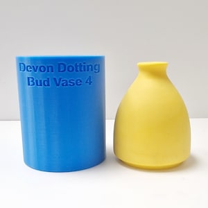 May include: A blue silicone mold for making a bud vase. The mold is labeled "Devon Dotting Bud Vase 4". A yellow silicone bud vase is next to the mold.