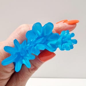 Könnte beinhalten: Ein blauer, stacheliger Stressball mit einer strukturierten Oberfläche. Das Spielzeug ist aus weichem, flexiblem Material gefertigt und soll zum Drücken und Manipulieren zur Stressbewältigung verwendet werden.