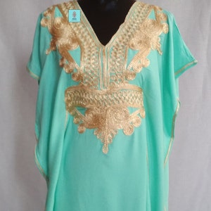 Puede incluir: Una kaftan verde menta con bordados dorados. El bordado presenta un patr&oacute;n geom&eacute;trico y motivos florales.