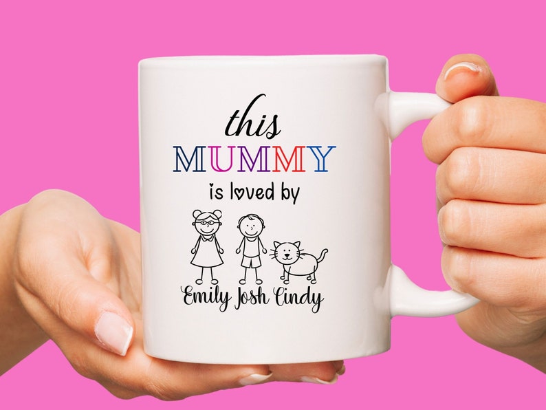 K&ouml;nnte beinhalten: Wei&szlig;e Keramiktasse mit einer Schwarzwei&szlig;illustration einer Familie mit einer Katze. Der Text lautet "this MUMMY is loved by Emily Josh Cindy".