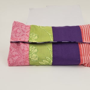 May include: A multi-colored fabric tissue box cover with pink, green, purple, and white stripes. The cover is folded closed.