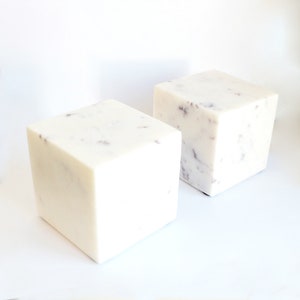 May include: Two white marble bookends with a speckled pattern. The bookends are cube shaped.