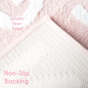 Puede incluir: Primer plano de una alfombra estampada en rosa y blanco con reverso antideslizante. La alfombra tiene un borde cosido de calidad. El texto "Quality Sewn Edge" y "Non-Slip Backing" son visibles en la imagen.