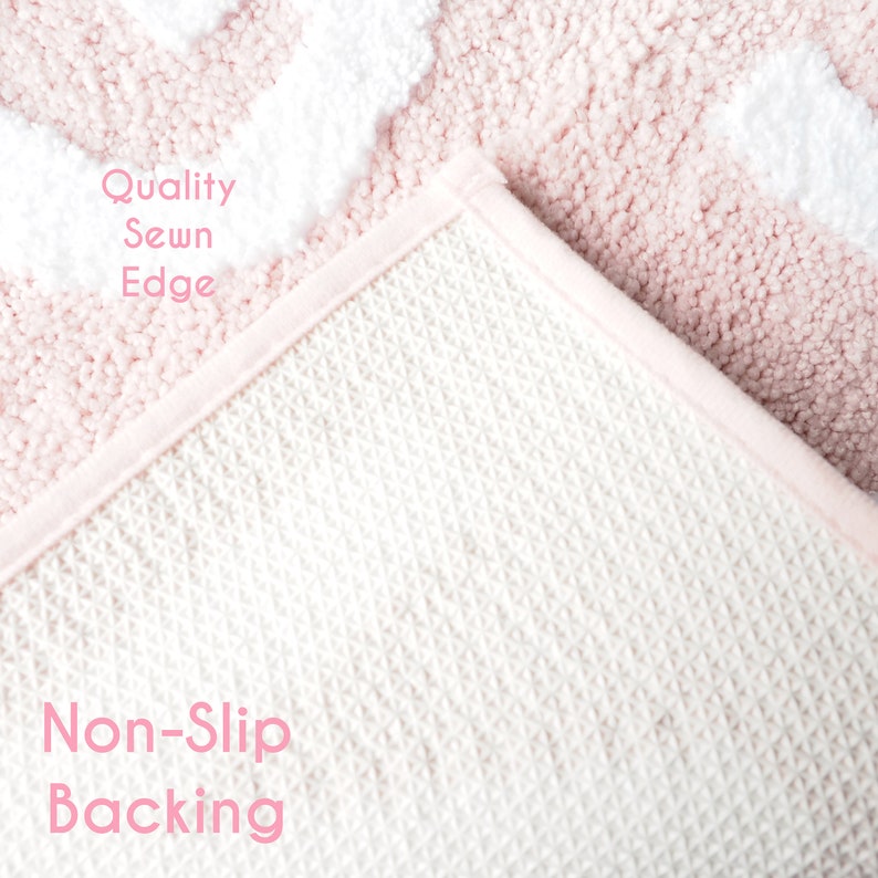 Puede incluir: Primer plano de una alfombra estampada en rosa y blanco con reverso antideslizante. La alfombra tiene un borde cosido de calidad. El texto "Quality Sewn Edge" y "Non-Slip Backing" son visibles en la imagen.