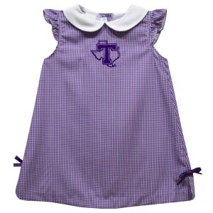 May include: A sleeveless purple and white gingham dress with a white collar and ruffle sleeves. The dress features a purple embroidered Texas-shaped logo with a "T" in the center and purple bows on the sides.