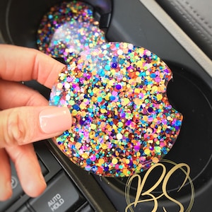 May include: A colorful glitter car coaster with a variety of colors including red, orange, yellow, green, blue, purple, and gold. The coaster is round and has a glossy finish.