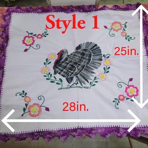 May include: White square tablecloth with a turkey and floral embroidery. The tablecloth is 28 inches wide and 25 inches high, with a purple crocheted border. The text "Style 1" is in red.
