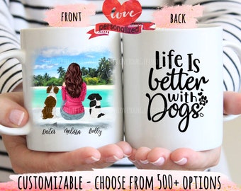 May include: White ceramic mug featuring a personalized illustration of a person with three dogs on a beach scene. The back of the mug has the text "Life is better with Dogs". The mug is held by a person.