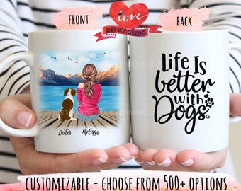 May include: White ceramic mug with a personalized image of a woman and a dog on a dock by a lake on the front. The back of the mug has the text "Life Is Better With Dogs" in black.