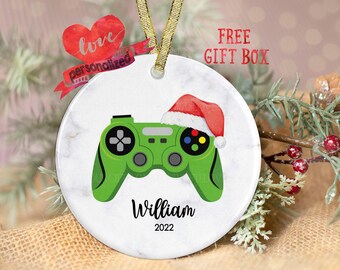 May include: White round Christmas ornament with a green video game controller and a red Santa hat. The ornament is personalized with the name "William" and the year "2022".