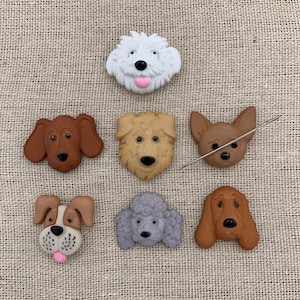 May include: Seven different dog breed face buttons, each with a unique expression. The buttons are made of a soft, pliable material and are perfect for adding a touch of whimsy to any project.