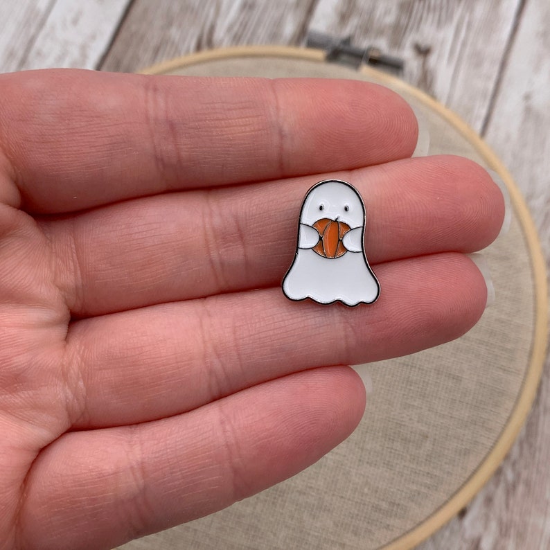 Peut inclure: Une &eacute;pingle en &eacute;mail de fant&ocirc;me blanc avec une petite citrouille orange dans ses mains.
