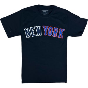 May include: Black t-shirt with a white outline and red and blue "NEW YORK" graphic.