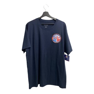 May include: A navy blue t-shirt with a circular graphic featuring a red, white, and blue American flag design. The graphic includes the text "City That Never Sleeps" and "New York City".