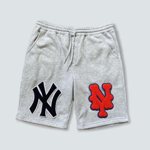 May include: Gray sweatpants with a black and white "NY" patch on the left leg and a red and blue "NY" patch on the right leg.