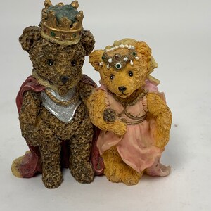 Può includere: Due statuette decorative a forma di orso. Uno è vestito da re, con corona e mantello, l'altro da principessa, con tiara e abito rosa. Le statuette presentano dettagli dipinti. Una coppia affascinante.