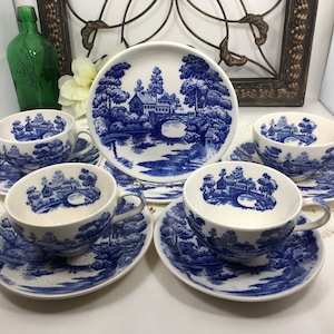 Puede incluir: Juego de cuatro tazas de té y platillos azules y blancos con un diseño de cabaña y puente. Las tazas y los platillos tienen un fondo blanco con un patrón floral azul.