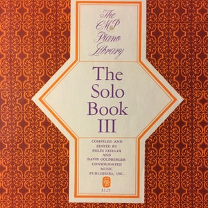 May include: The Solo Book III, a music book from The MP Piano Library, features a cream-colored diamond-shaped label with orange trim. The cover has a repeating orange and brown pattern. The text includes the title, the names of the editors, and the publisher.