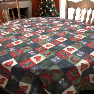 May include: A round Christmas tablecloth with a repeating pattern of red hearts, green Christmas trees, blue bells, and white snowflakes on a checkered background of red, green, and blue squares. The tablecloth is on a wooden table.