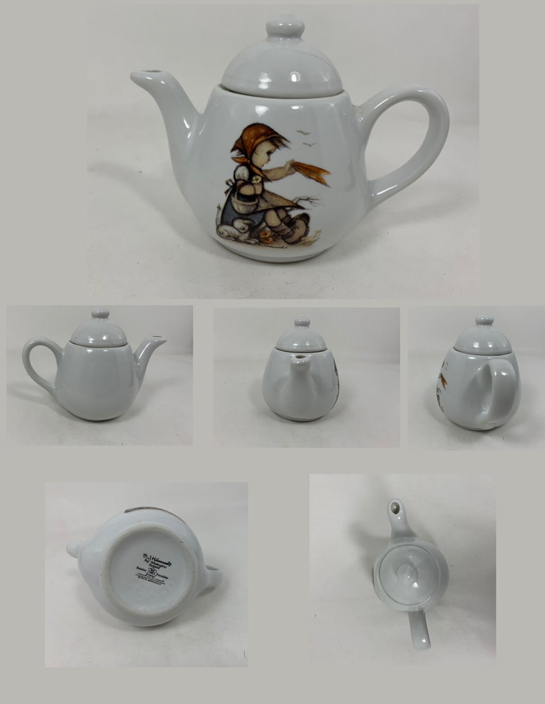Op de afbeelding: Witte porseleinen theepot met een ontwerp van een meisje en vogels. De theepot heeft een deksel en een tuit. Op de bodem van de theepot staat in bruine letters "Hummel by Goebel Made in Germany".
