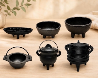 May include: A collection of six black cast iron vessels including three open bowls with tripod legs and three lidded pots with metal handles. The items vary in shape and size, featuring textured surfaces and sturdy construction for tabletop use.