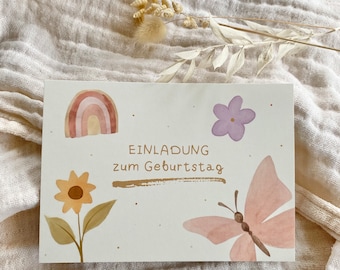 Peut inclure: Une carte blanche avec un arc-en-ciel aquarelle, un tournesol, une fleur violette et un papillon. La carte dit "Einladung zum Geburtstag" qui signifie "Invitation à l'anniversaire" en allemand.