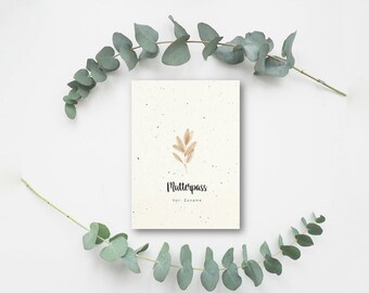 Peut inclure: Une carte blanche avec une illustration de branche brune et le texte "Mutterpass" et "Vor-Zuname" sur un fond blanc avec des branches d'eucalyptus vertes de chaque côté.