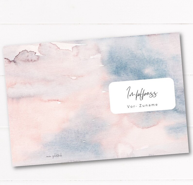 May include: A watercolor-style cover with a soft, blended design in shades of pink and blue. The cover features a white rectangular label with the words "Impfpass" and "Vor-Zuname" in elegant script. The artist's signature is in the lower left corner.